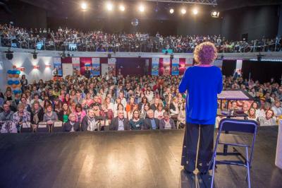 Un groupe de personnes en tenue formelle pose sur une scène lors d'un événement avec un écran affichant des logos en arrière…