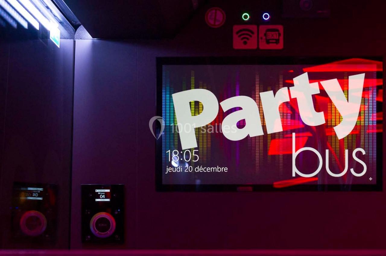 Écran lumineux affichant ’Party bus’ avec des effets colorés, entouré de lumières et d'équipements audio.