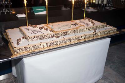 Un groupe de personnes en tenue formelle pose sur une scène lors d'un événement avec un écran affichant des logos en arrière…