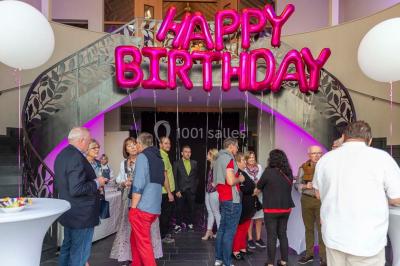Un groupe de personnes en tenue formelle pose sur une scène lors d'un événement avec un écran affichant des logos en arrière…