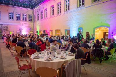 Un groupe de personnes en tenue formelle pose sur une scène lors d'un événement avec un écran affichant des logos en arrière…
