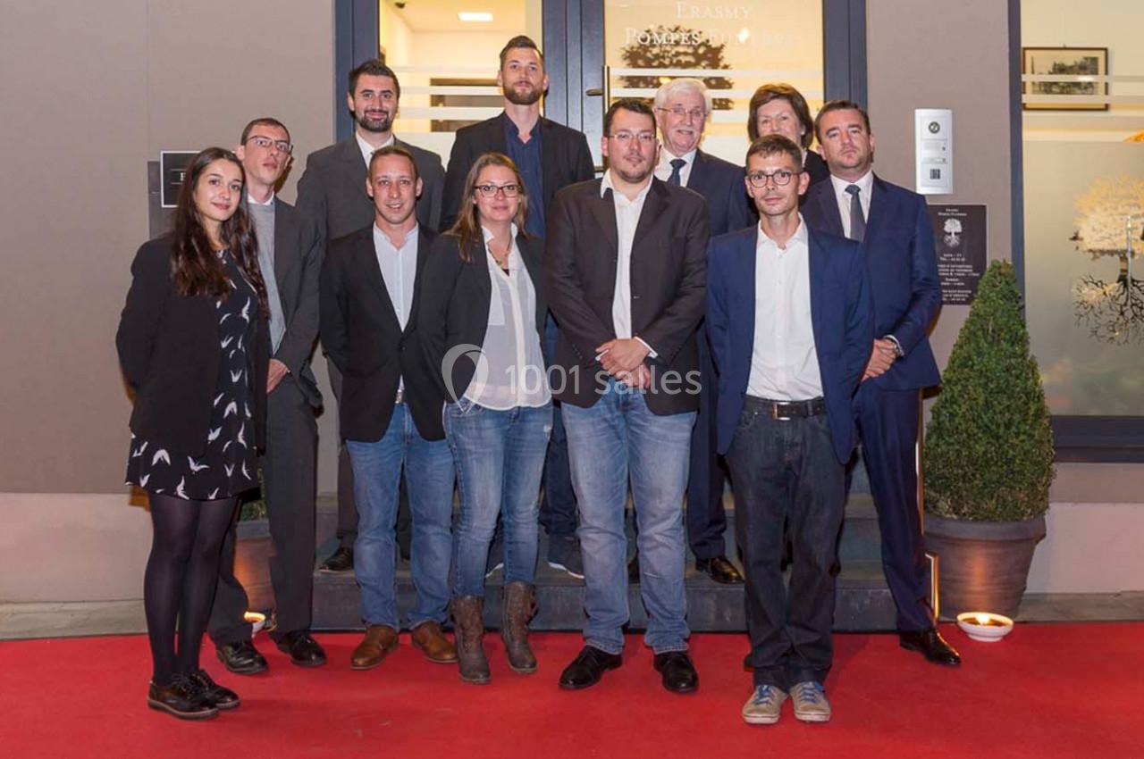 Un groupe de personnes posant sur un tapis rouge devant l'entrée d'un bâtiment.