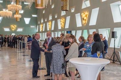 Un groupe de personnes en tenue formelle pose sur une scène lors d'un événement avec un écran affichant des logos en arrière…