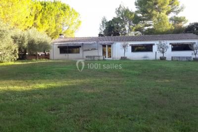 Un champ avec des vaches noires paissant, entouré de clôtures en bois et bordé d'arbres.