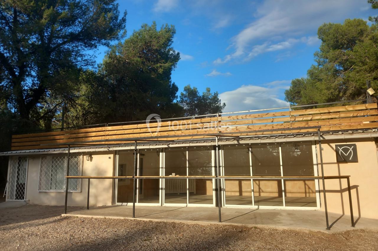 Bâtiment avec façade vitrée, structure métallique et enseigne en forme de cœur, entouré d'arbres sous un ciel dégagé.