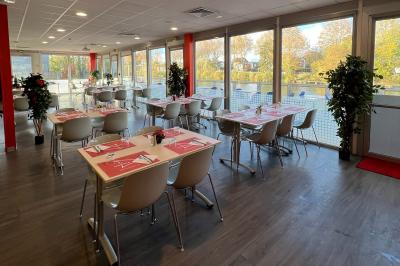 Salle de conférence lumineuse avec des participants assis, une présentation projetée et une table de buffet au premier plan.