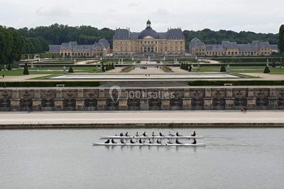 Un groupe de personnes souriantes pose dans une salle avec des rameurs et un écran projeté en arrière-plan.