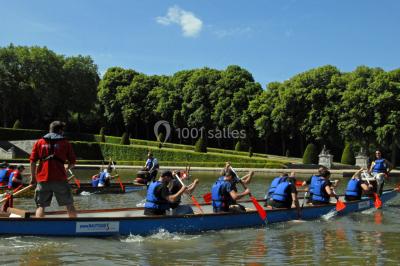 Un groupe de personnes souriantes pose dans une salle avec des rameurs et un écran projeté en arrière-plan.