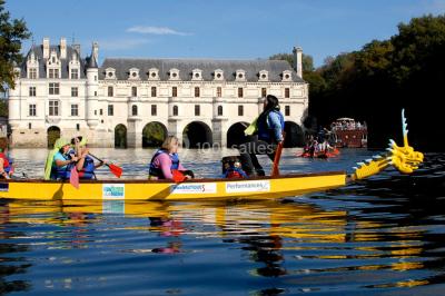 Un groupe de personnes souriantes pose dans une salle avec des rameurs et un écran projeté en arrière-plan.