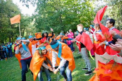 Un groupe de personnes souriantes pose dans une salle avec des rameurs et un écran projeté en arrière-plan.