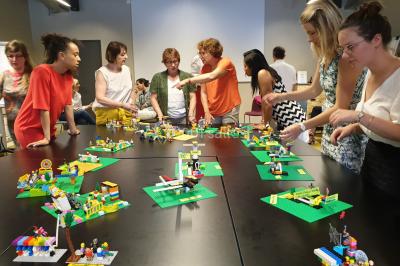 Un groupe de personnes souriantes pose dans une salle avec des rameurs et un écran projeté en arrière-plan.