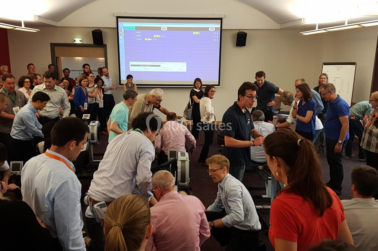 Des personnes participent à une activité collaborative dans une salle de conférence équipée d'un écran de projection.