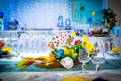 Table décorée avec des fleurs blanches, des ornements royaux ’Queen’ et ’King’, et un fond scintillant.