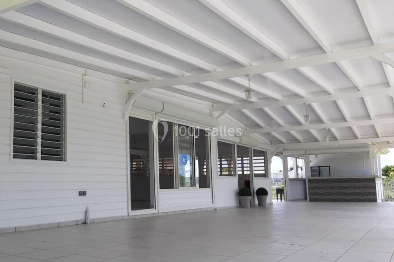 Terrasse couverte spacieuse avec plafond blanc, grandes baies vitrées, comptoir et vue dégagée à l'arrière-plan.
