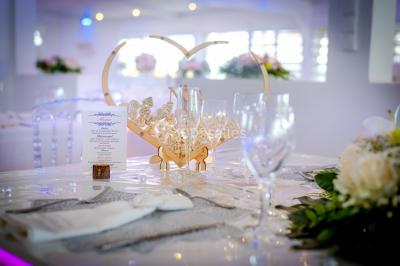 Table décorée avec des fleurs blanches, des ornements royaux ’Queen’ et ’King’, et un fond scintillant.