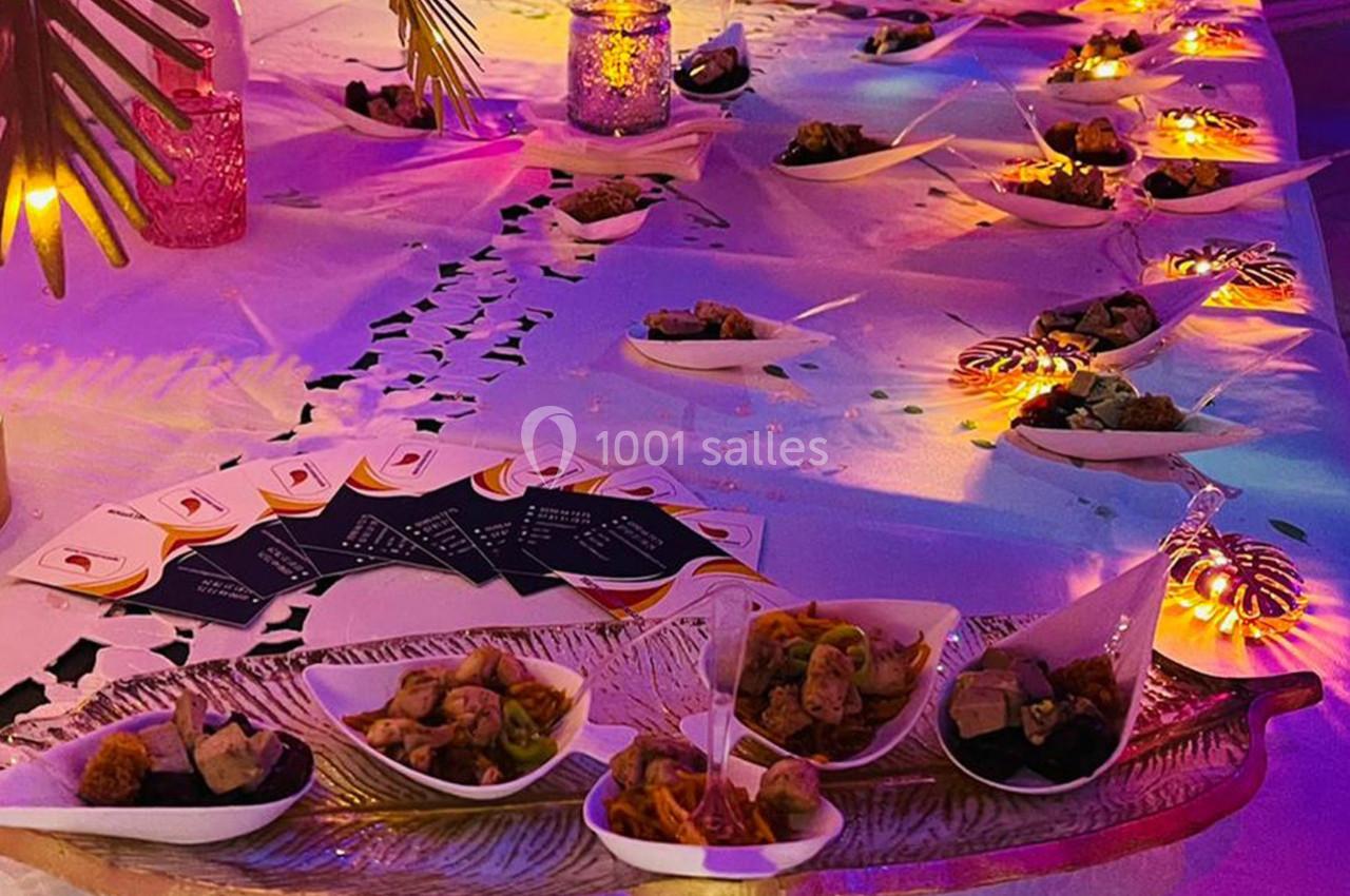 Table décorée avec des lumières colorées, présentant des amuse-bouches dans des coupelles blanches sur un plateau doré.