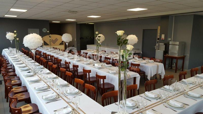 Location salle Bonneuil-sur-Marne (Val-de-Marne) - Salle des Petits Carreaux #11 Salle de réception avec de longues tables dressées, nappes blanches, vaisselle élégante et décorations florales.