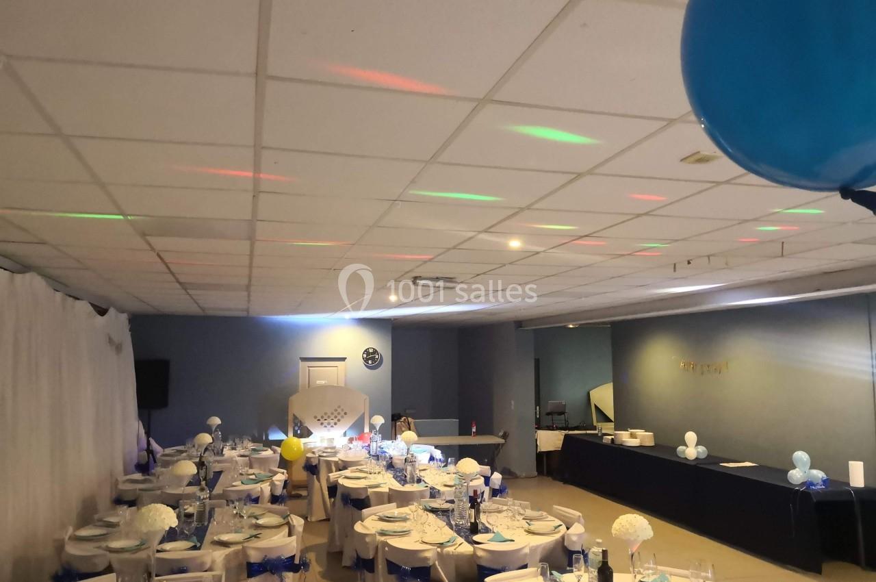 Location salle Bonneuil-sur-Marne (Val-de-Marne) - Salle des Petits Carreaux #3 Salle de réception décorée avec des tables dressées, nappes blanches et éléments bleus, éclairage tamisé.