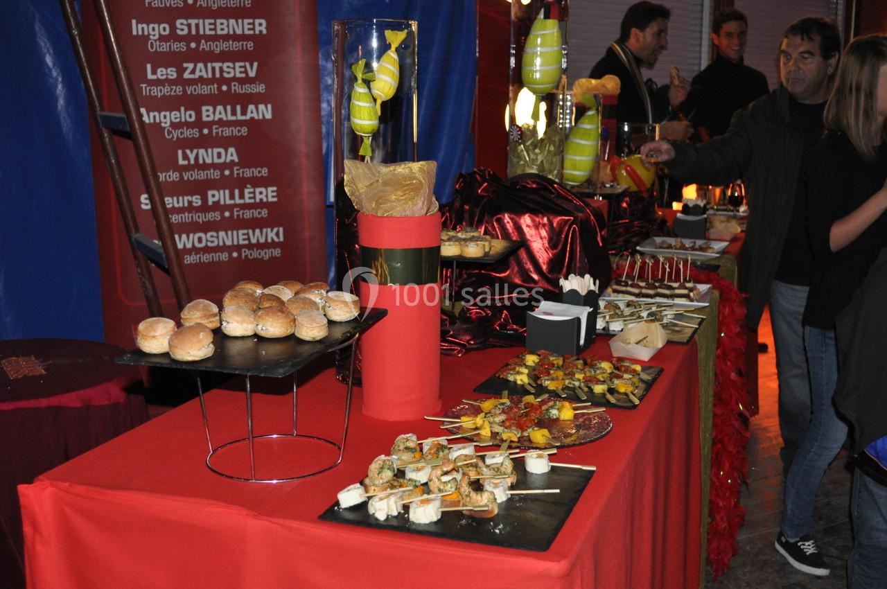 Buffet coloré avec divers amuse-bouches, brochettes et pains disposés sur une table rouge lors d'un événement.