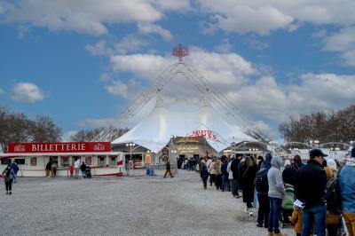 File d'attente devant un chapiteau de cirque blanc avec un guichet de billetterie sur la gauche.