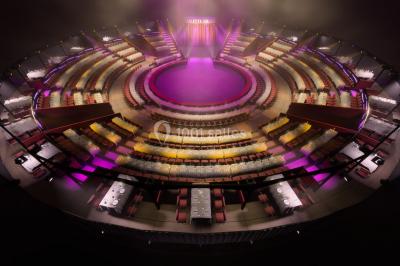 Personnes dansant sous des éclairages colorés dans une salle sombre avec des gradins en arrière-plan.