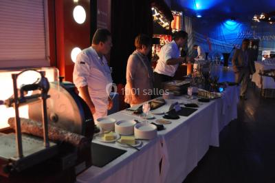 Personnes dansant sous des éclairages colorés dans une salle sombre avec des gradins en arrière-plan.