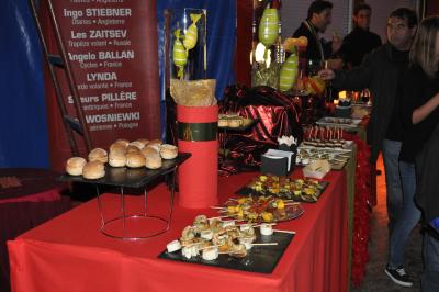 Chapiteau blanc et rouge monté sur un terrain en gravier, entouré d'arbres et de structures similaires.