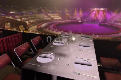 Grand chapiteau blanc et rouge installé sur un terrain gravillonné, entouré d'arbres et de structures similaires.