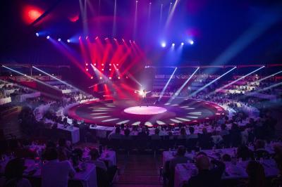 Grand chapiteau blanc et rouge monté sur un terrain en plein air, entouré d'arbres et de structures secondaires.
