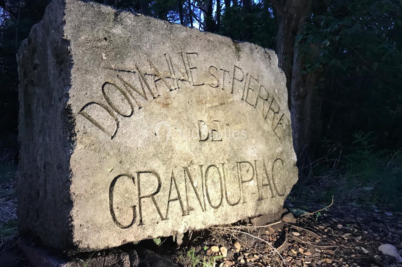 Pierre gravée indiquant ’Domaine Saint Pierre de Granoupiac’, éclairée dans un environnement boisé.