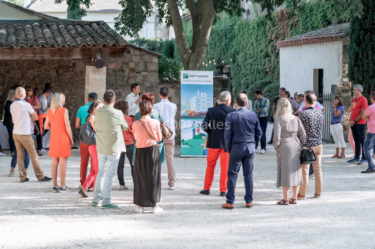 Un groupe de personnes debout en extérieur, rassemblé devant un panneau d'information sous des arbres.