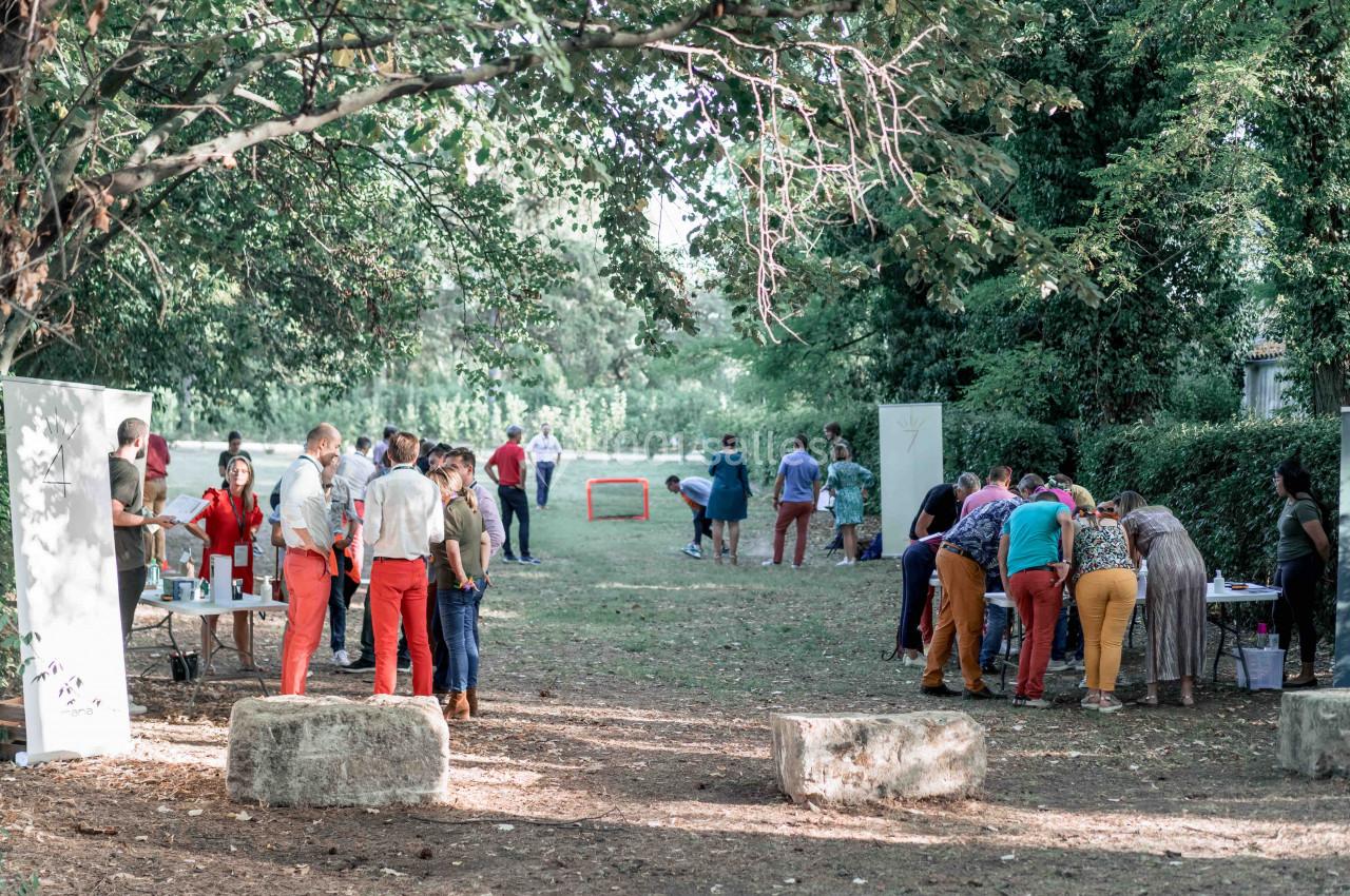 Des personnes participent à des activités en plein air dans un espace boisé, avec des stands et des jeux.