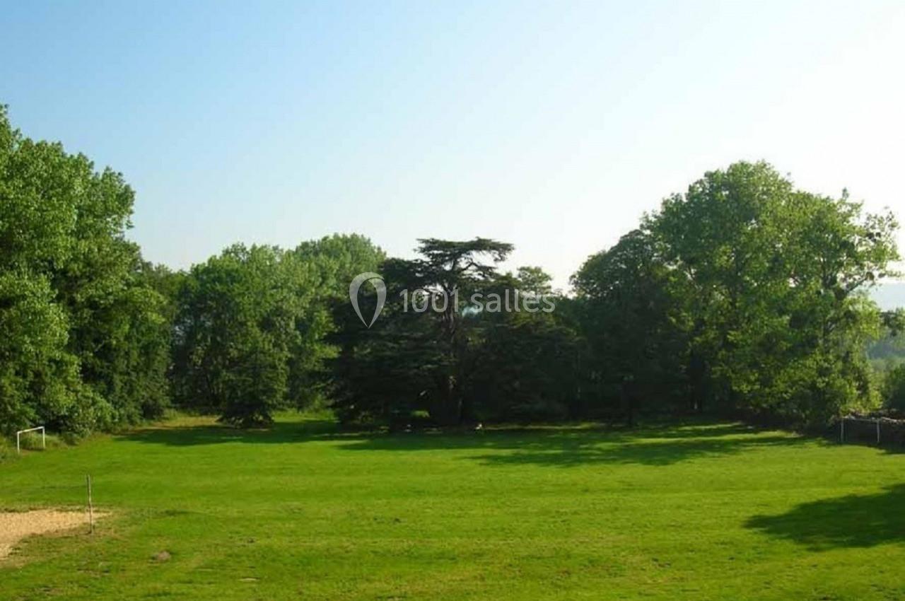 Vue d'un grand espace vert avec des arbres en arrière-plan sous un ciel dégagé.