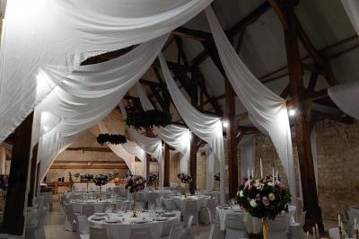 Voiture ancienne noire décorée de fleurs, stationnée sur une allée pavée dans un cadre champêtre.
