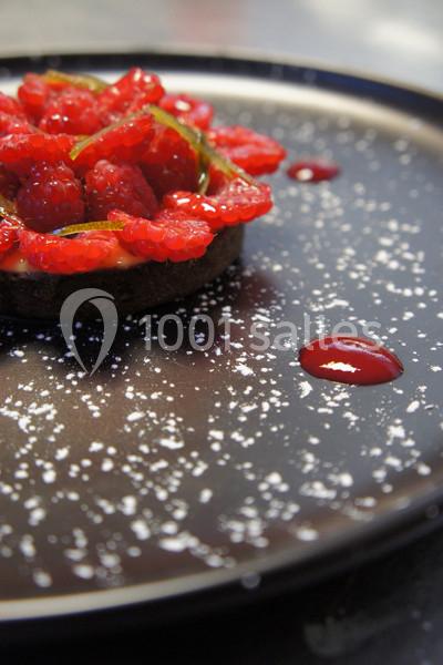 Traiteur Forest-sur-Marque (Nord) - Auberge du Tilleul #30 Tartelette garnie de framboises fraîches sur une assiette noire décorée de sucre glace et de gouttes de coulis.