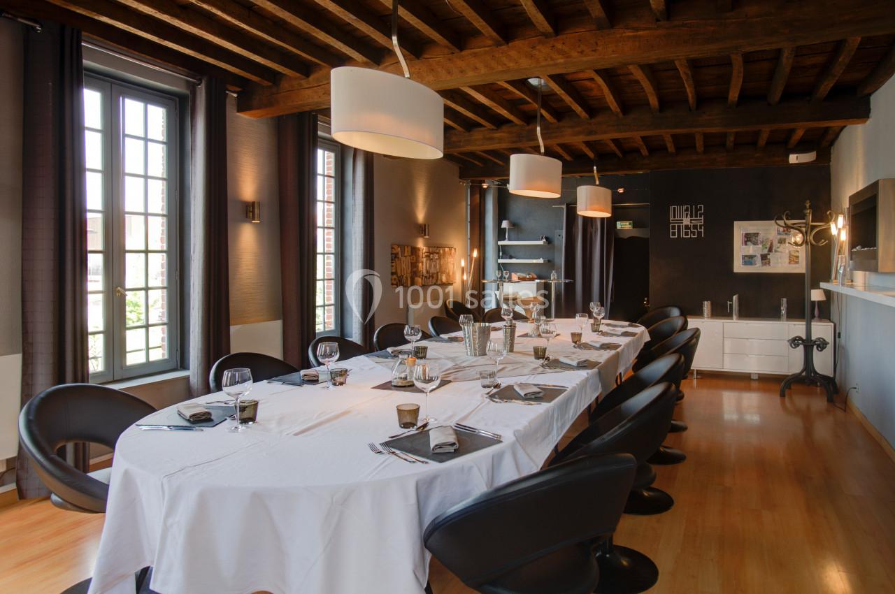 SALON PICASSO - 20 PERSONNES - Repas de famille ou séminaire Salle à manger élégante avec une grande table dressée, chaises noires, plafond en bois et lumière naturelle.