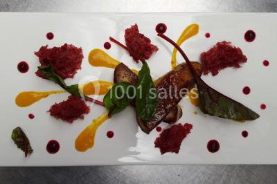 Dessert roulé recouvert de glaçage rouge, garni de rondelles de banane, avec des touches de coulis sur l'assiette blanche.