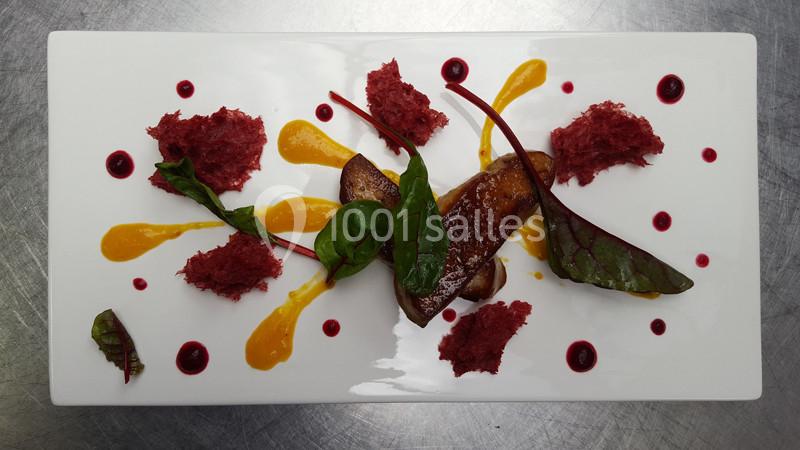 Assiette gastronomique avec foie gras, purées colorées, feuilles de betterave et décorations artistiques sur fond blanc.
