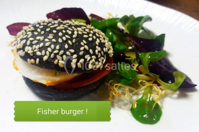 Dessert roulé recouvert de glaçage rouge, garni de rondelles de banane, avec des touches de coulis sur l'assiette blanche.