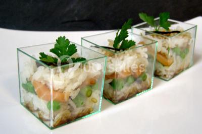 Dessert roulé recouvert de glaçage rouge, garni de rondelles de banane, avec des touches de coulis sur l'assiette blanche.