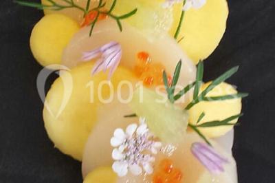 Dessert roulé recouvert de glaçage rouge, garni de rondelles de banane, avec des touches de coulis sur l'assiette blanche.