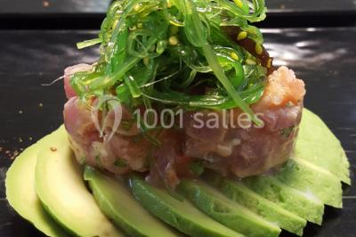 Dessert roulé recouvert de glaçage rouge, garni de rondelles de banane, avec des touches de coulis sur l'assiette blanche.