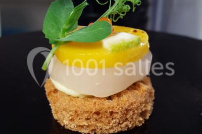 Dessert roulé recouvert de glaçage rouge, garni de rondelles de banane, avec des touches de coulis sur l'assiette blanche.