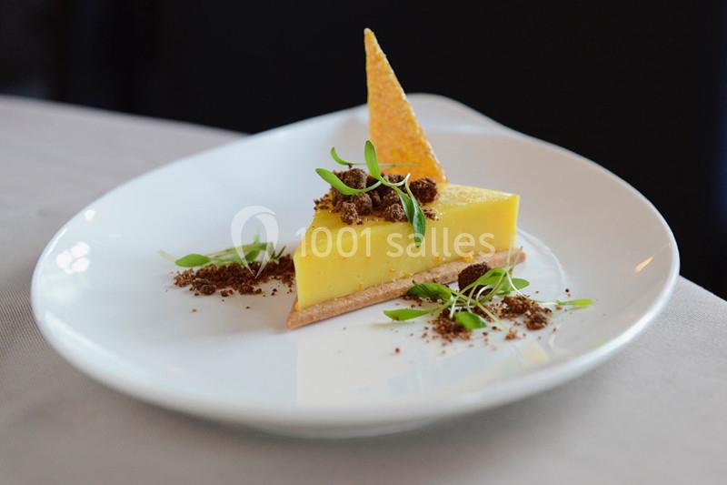 Part de tarte au citron garnie de miettes de chocolat, de pousses vertes et d'un triangle croustillant, servie sur une…