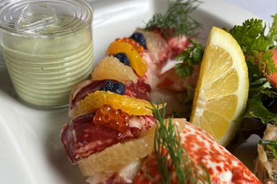 Dessert roulé recouvert de glaçage rouge, garni de rondelles de banane, avec des touches de coulis sur l'assiette blanche.