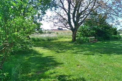 Chambre mansardée avec deux lits simples, un bureau en bois, une chaise blanche et une fenêtre de toit.