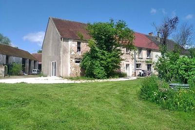 Chambre mansardée avec deux lits simples, un bureau en bois, une chaise blanche et une fenêtre de toit.