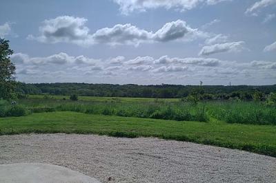 Chambre mansardée avec deux lits simples, un bureau en bois, une chaise blanche et une fenêtre de toit.