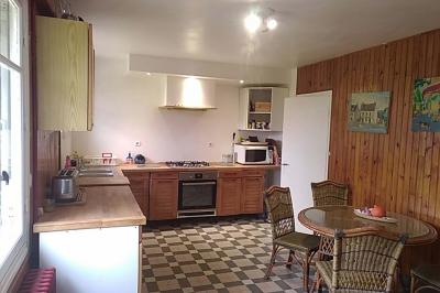 Chambre mansardée avec deux lits simples, un bureau en bois, une chaise blanche et une fenêtre de toit.