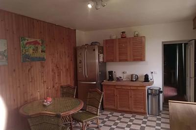 Chambre mansardée avec deux lits simples, un bureau en bois, une chaise blanche et une fenêtre de toit.